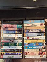 Full view of two vertical stacks of VHS tapes beside black storage unit