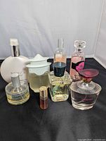 Group shot of eight visible perfume bottles on black backdrop