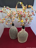 Two crochet-covered bottles with berry stems front view