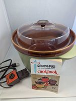 slow cooker with lid, control cord and cookbook front view
