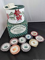 Rival poinsettia crock with cord on top of original box, nine Yankee Candle wax tarts arranged in front