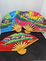 Three fans displayed open showing colors and landscapes