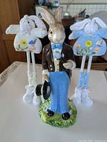 Front view of ceramic rabbit figurine flanked by two fabric plush bunnies