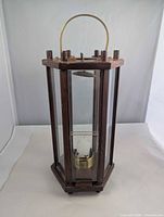 Front view of hexagonal wood and glass candle lantern showing hanging handle and candle platform