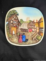 Front view of entire square rounded chalkware wall plaque showing full Victorian town scene relief