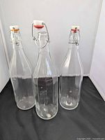 Front view of three clear glass bottles with stoppers