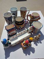 Group of seven mugs, ceramic dish, and two resin figurines