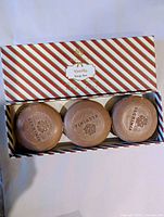 Striped box opened showing three round embossed soaps