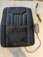 Front view of black plush massage cushion with attached remote and cord
