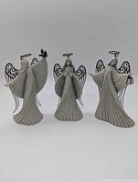 Front view of all three gray art stone angel figurines with metal wings and halos