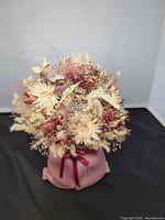 Front view of pink ceramic pocket vase with dried floral arrangement