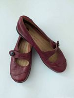 Pair of burgundy leather Mary Jane flats angled overlap