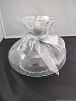 Front view of clear hammered glass bag-shaped vase with ribbon