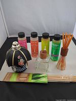 Full lot view showing five refill bottles, decorative lamp, square glass bottle with wood cap, reed sticks in holder and spare reed sticks pack