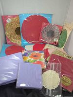 Group of sealed doily and napkin packs showing variety of colors and shapes