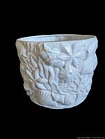 Full view of white ceramic planter showing overall shape and relief decoration