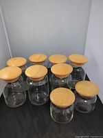 front view showing nine of ten glass canisters with wood lids