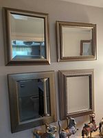 Four pewter tone framed wall mirrors hung together