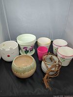 All eight ceramic and stoneware planters, saucer and hanging planter arranged together