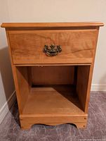 Front view of maple night stand showing drawer, open shelf, scalloped base