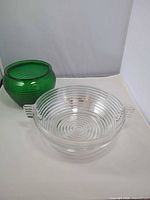 Clear ribbed glass bowl and green ribbed vase side by side