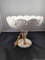Full view of milk glass pedestal fruit bowl showing scalloped rim and tassel accent