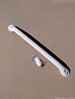 Single Moen white grab bar with hardware bag on concrete surface