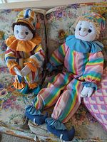 Both clown dolls seated on floral couch