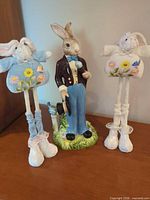 Group view: ceramic rabbit figurine flanked by two plush bunny ornaments