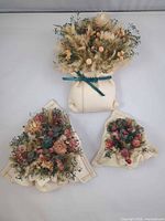 Front view of all three ceramic wall pocket vases showing size comparison and florals