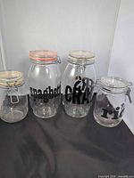 Four clear glass clamp-lid canisters grouped together