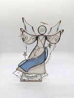 Front view of stained glass angel figurine showing white and blue glass panels, wings, halo, bead garlands, metal stars, and base