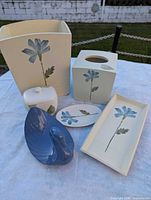 Group shot of six visible items: wastebasket, tissue cover, rectangular tray, lidded jar, oval dish, blue swan
