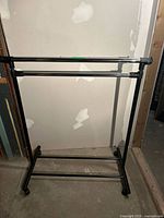 Full view of black and chrome double-bar garment rack on casters