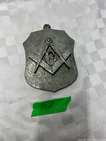 Front view of cast metal shield plaque showing Masonic emblem and hanging loop
