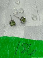 Close-up of both sterling silver green stone stud earrings with posts and plastic backs