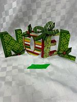 Front view of metal NOEL sign showing full word and patterns