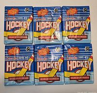 Six sealed blue 1991-92 O-Pee-Chee NHL Hockey wax packs displayed in two rows
