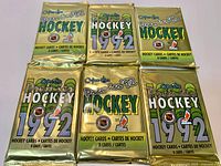 Six unopened gold foil packs arranged in two rows