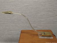 Full side view of curved lucite and brass table lamp on wood surface