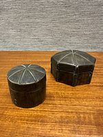 Both patinated brass boxes closed, showing lid designs and overall form
