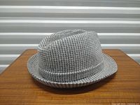 Front and side view of grey/white houndstooth Kangol hat on table