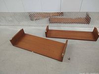 Two teak shelves laid flat showing top surfaces and corner mounting clips