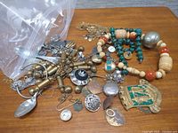 All items spread on table including necklaces, medal, spoons, charms