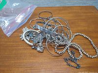 Pile of mixed silver-tone bangles, beaded necklace and chain necklace on table