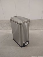 Full view front left of stainless steel pedal trash can