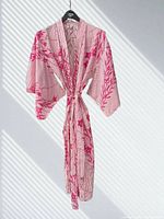 Front view of pink and white cotton kimono robe hanging with belt