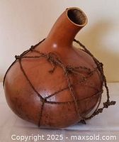 Oblique view of gourd showing neck opening and rope netting