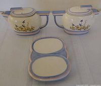 Front view of two matching teapots with lids and divided serving dish