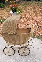 Side view of wicker baby carriage with hood raised showing overall form